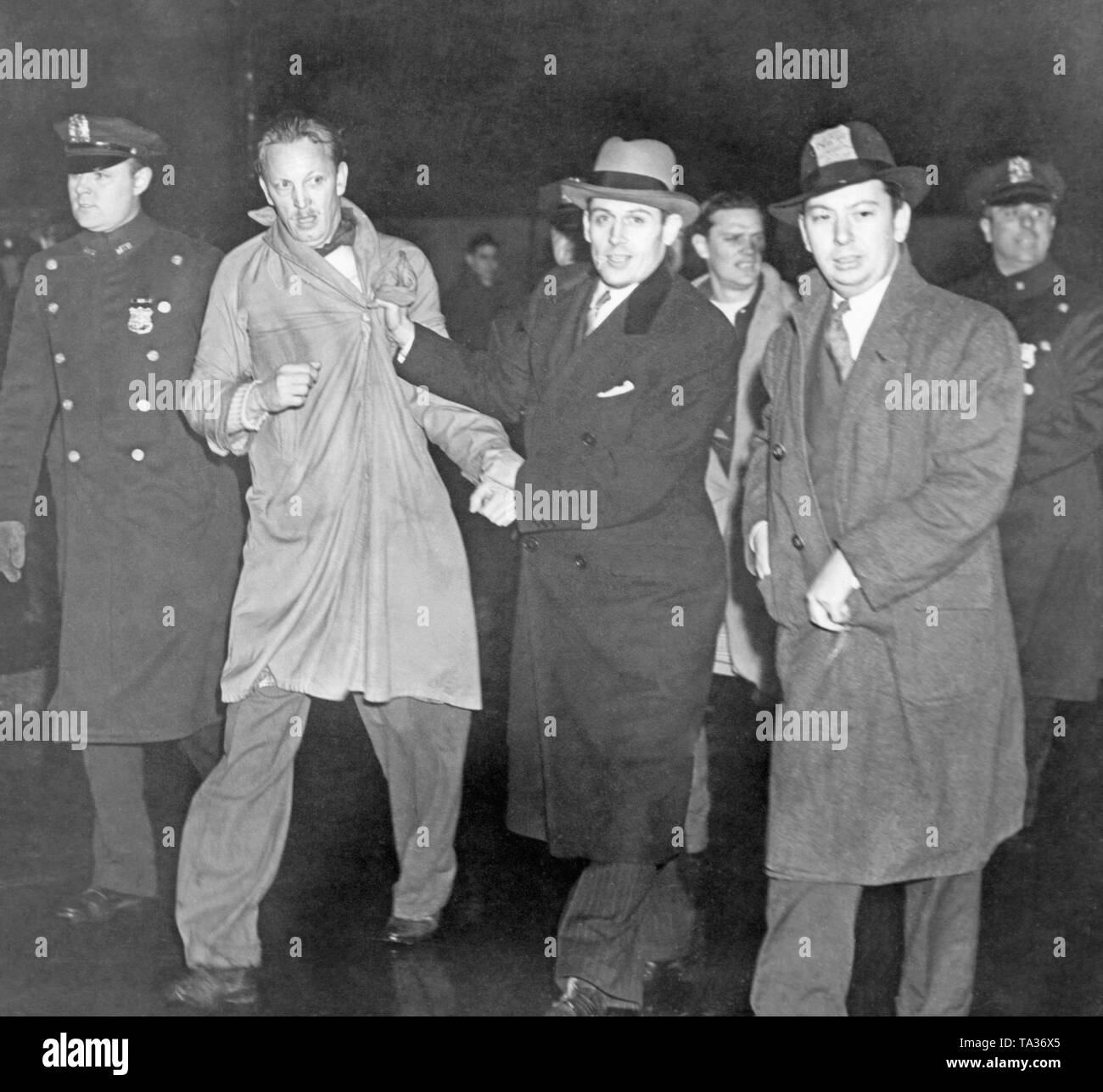 Policemen in uniform and civilian clothes lead away a protester for the rescue and better treatment of refugees of the Spanish Civil War in front of the French Consulate on 5th Avenue (49th Street) on March 29, 1940. The gathering was organized by the Emergency Committee to Save Spanish Refugees. Stock Photo