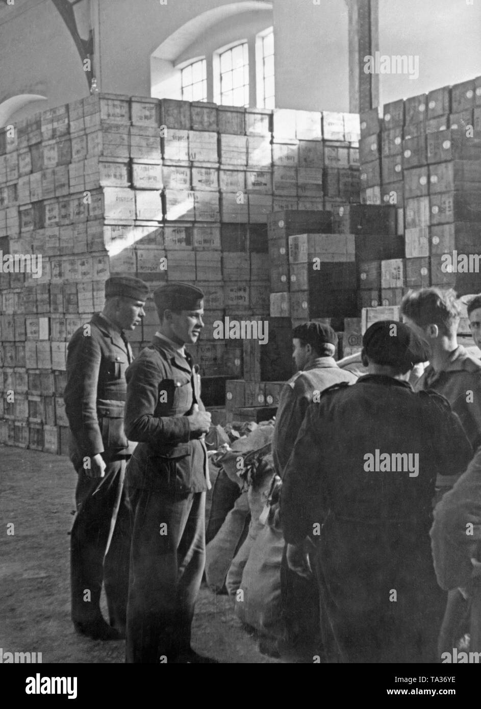 Undated photo of a camp of the German Condor Legion in an unknown place in Spain during the Spanish Civil War. In the background there are boxes with food. In the foreground, German supply officers in the uniform of the Condor Legion. Stock Photo