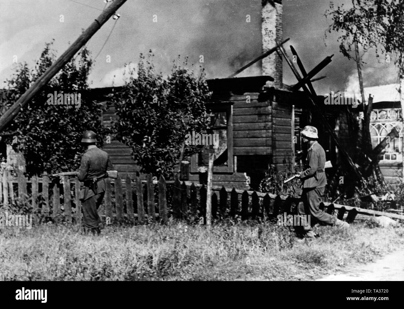 German soldiers search a burning village for Soviet soldiers at the northern sector of the Eastern Front (presumably in Lithuania or in Northern Belarus). In the course of Operation Bagration, the Red Army forces the Wehrmacht westward in the summer of 1944. Only occasionally can individual positions, such as a village, be held by the Wehrmacht for a short period of time. Photo of the Propaganda Company (PK): war correspondent Weber. Stock Photo