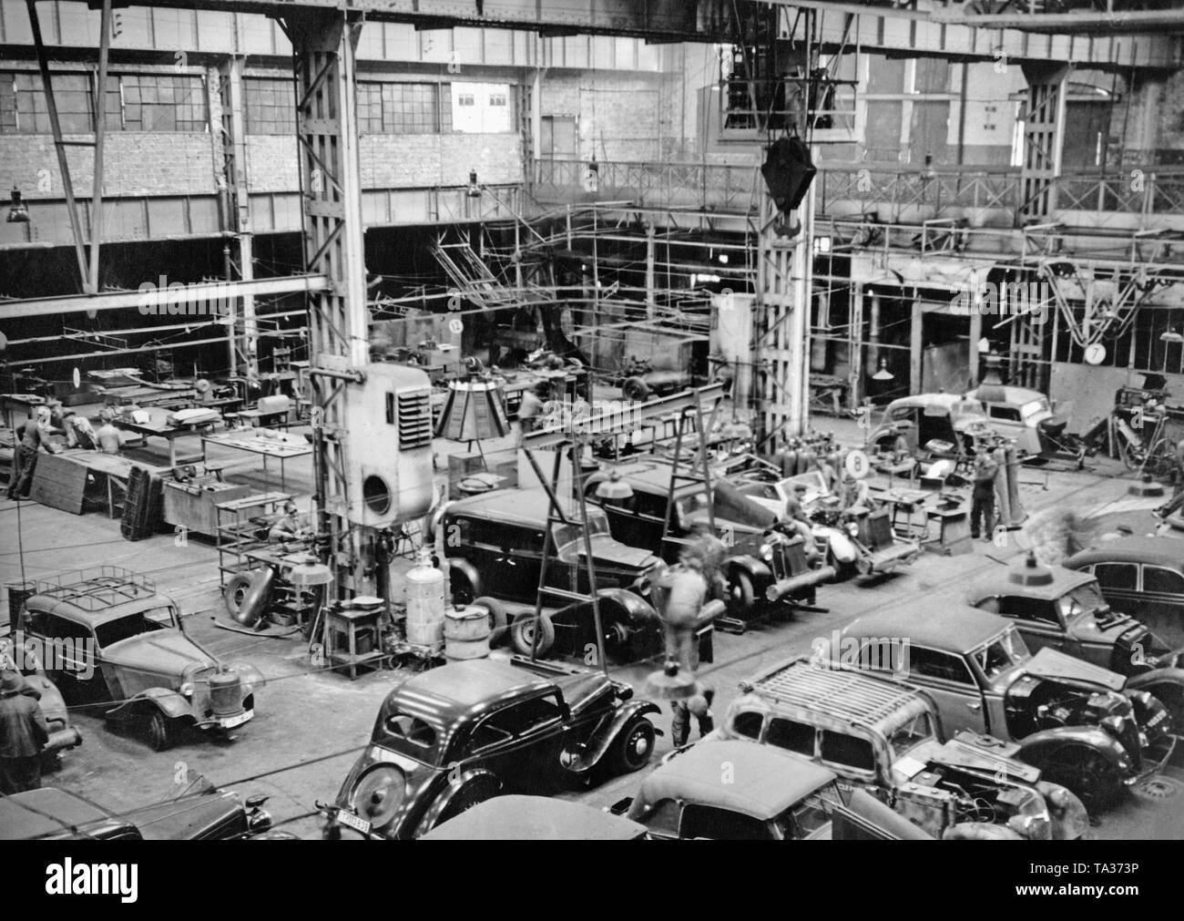 In 1945 the Adlerwerke received through the American military government permission for the production of spare parts for automobiles, bicycles and typewriters. The picture shows a view of one of the former workshops with cars waiting to be repaired. Stock Photo
