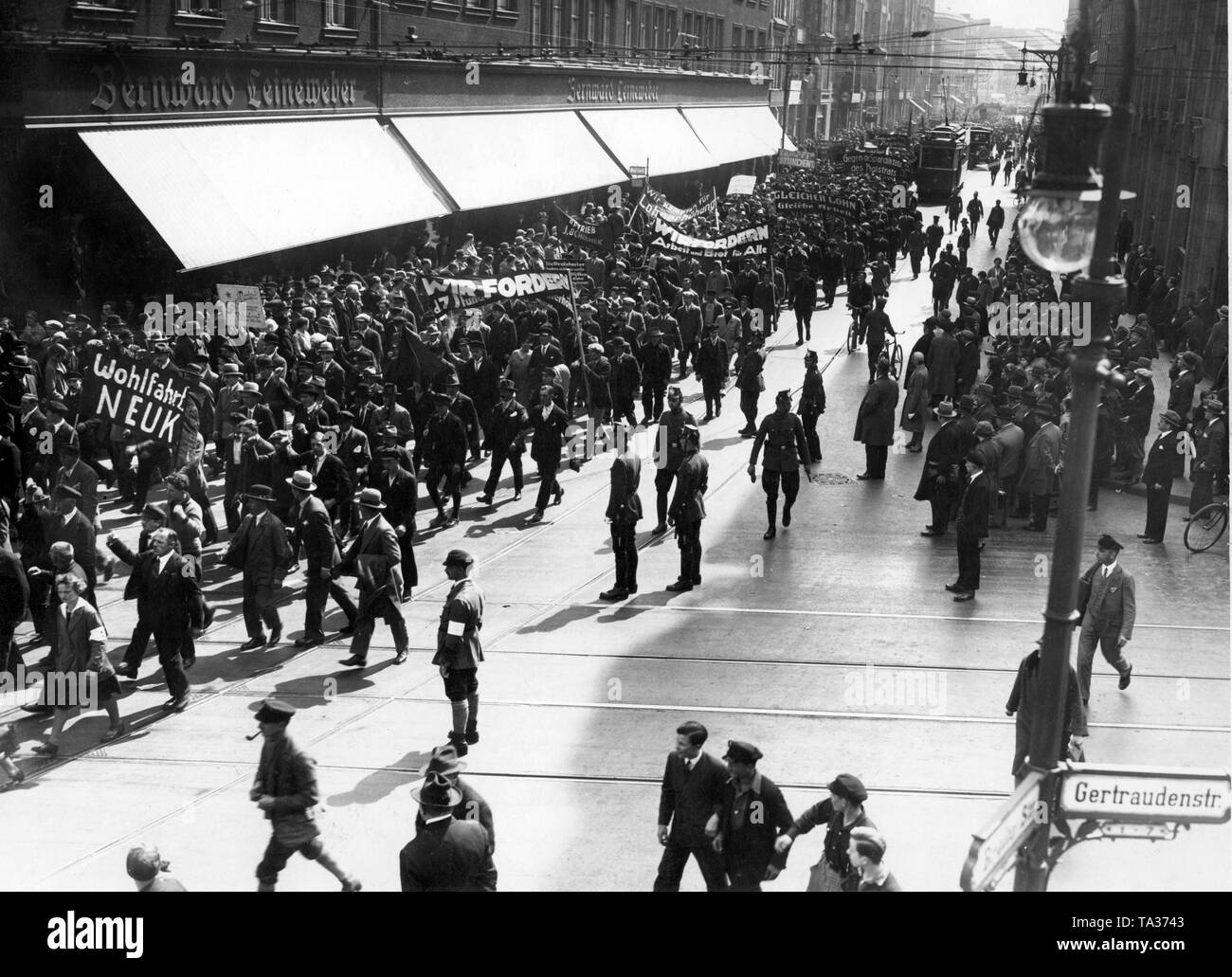 Supporters of the Communist Party of Germany (KPD) march through the streets on the Museum Island in Berlin with banners and flags. The demonstration rally is accompanied by police officers. On the banners it says: 'We demand work and bread for all'. Stock Photo