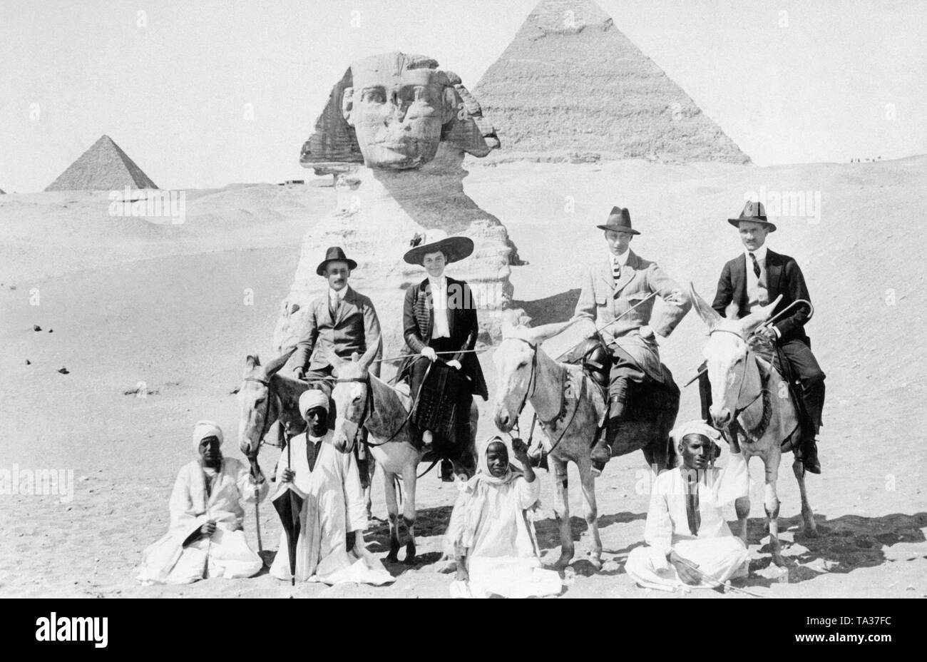 The German Crown Prince William, the eldest son of Emperor William II, and his wife Cecilia pose on donkeys in front of the Sphinx in Giza, in the background the pyramids. A trip to Egypt was considered an expensive and extravagant adventure at that time. Stock Photo