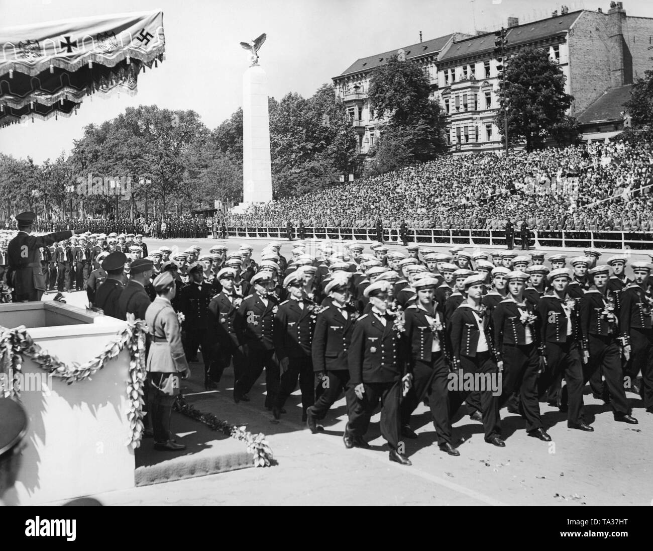 Photo of a marine formation (sailors and corporals) marching in front of officers of the Wehrmacht and leader, Adolf Hitler (under a canopy), at the parade of the Condor Legion on the East-West Axis (former Chalottenburger Chaussee, today Strasse des 17. Juni ) in front of the Technische Universitaet on June 6, 1939. Stock Photo