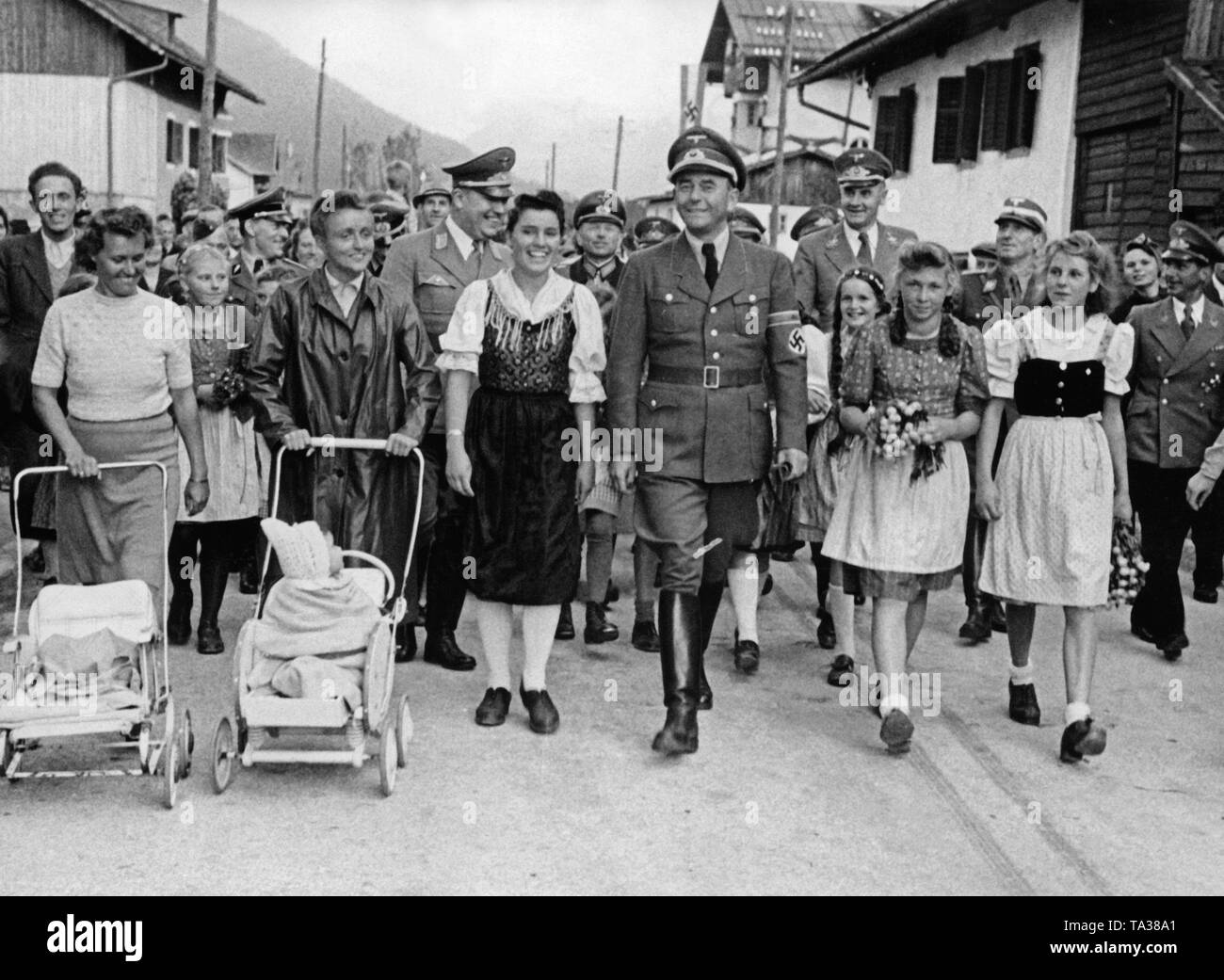 Albert Speer (front) visits Heinz Guderian (left behind him) Seefeld in Tirol. The place served as a resort for soldiers of the armored corps and for armament workers, who were engaged in tank manufacturing. Here they walk through the streets of the village. In the second row at left, before Heinz Guderian, the Gauleiter of Tirol-Vorarlberg Franz Hofer. Stock Photo