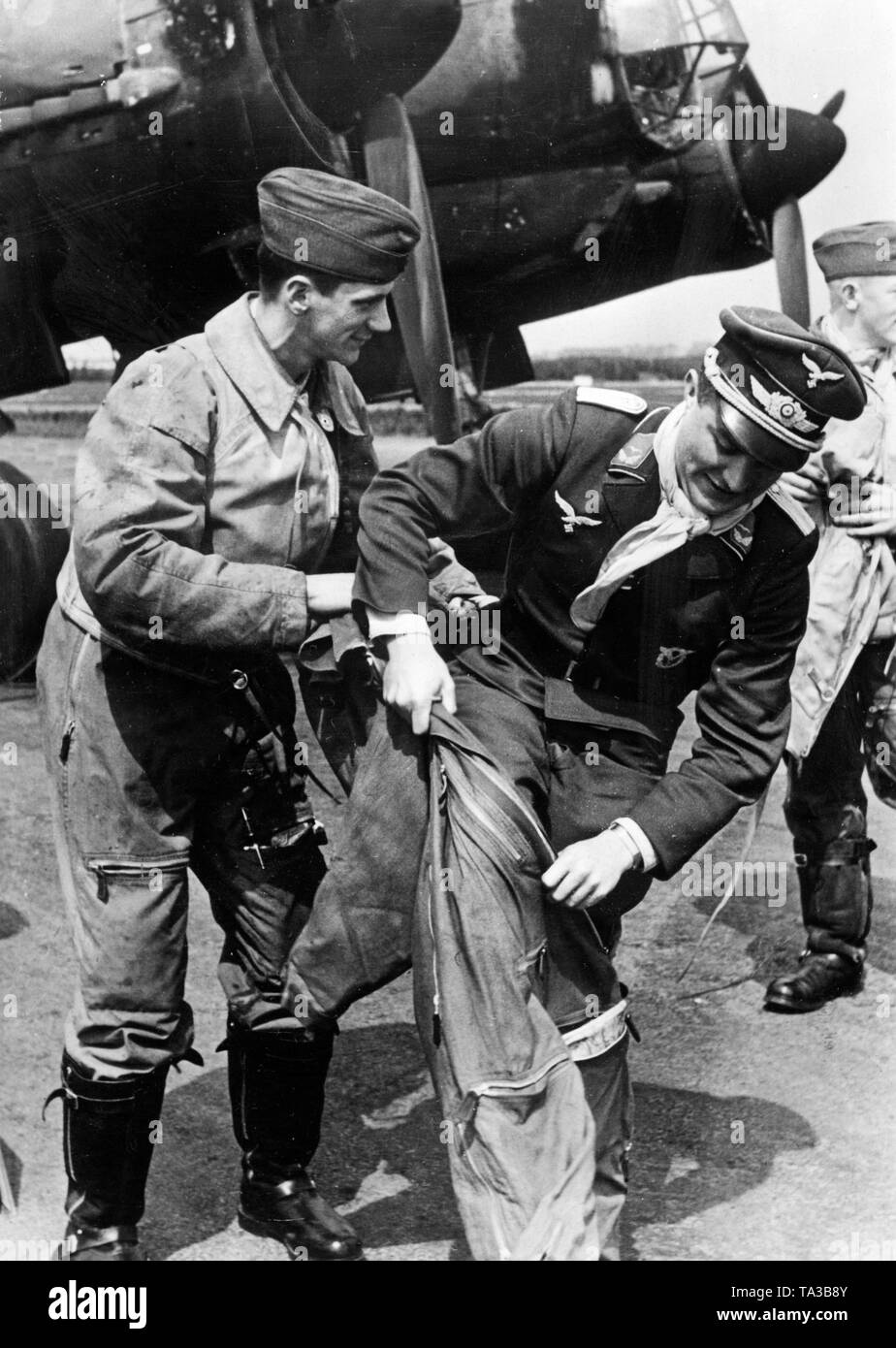 An officer of the Luftwaffe takes his overall on his uniform. In the background, a Dornier Do 17 combat aircraft. Shortly, a deployment in France was about to begin. Photo: war correspondent Stempka. Stock Photo