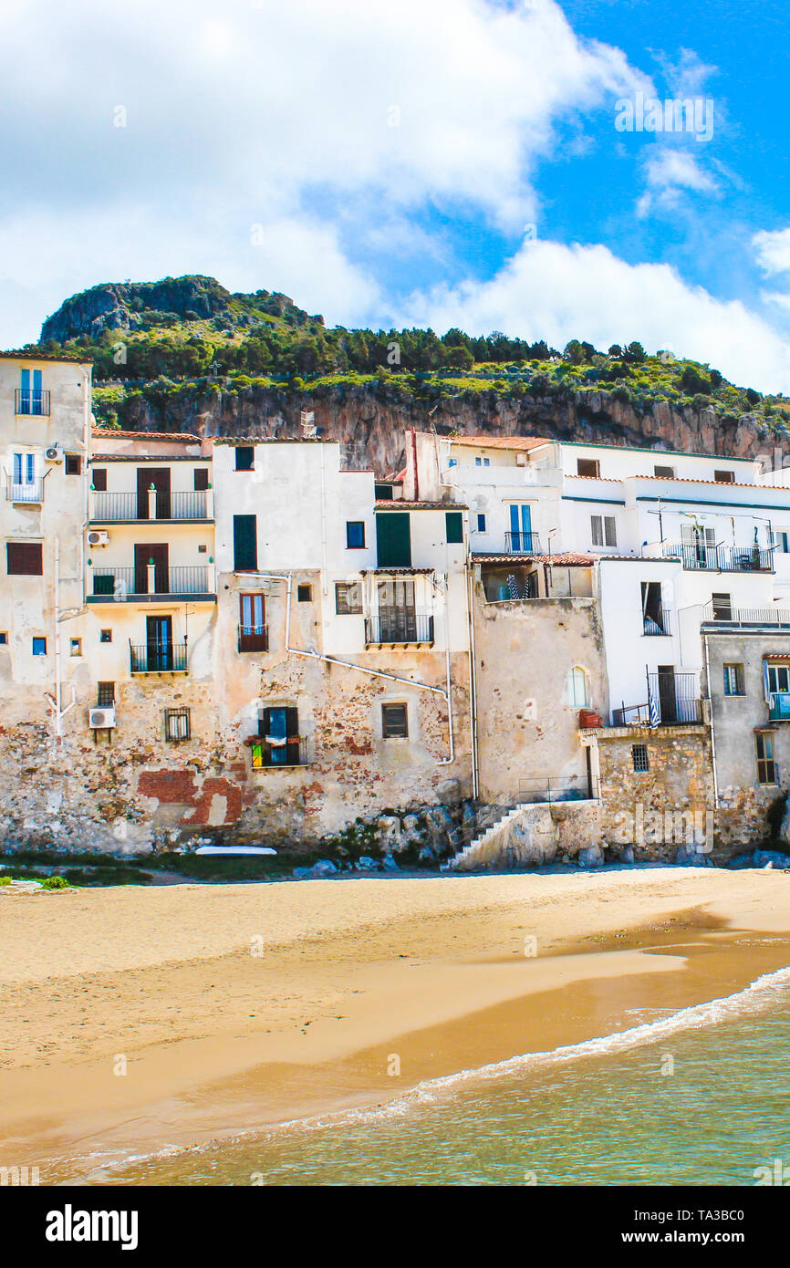 Beautiful old houses overlooking the Tyrrhenian sea in Cefalu, Sicily, Italy. Captured on vertical picture with rock behind the historical city. Cefalu is a popular vacation destination. Stock Photo