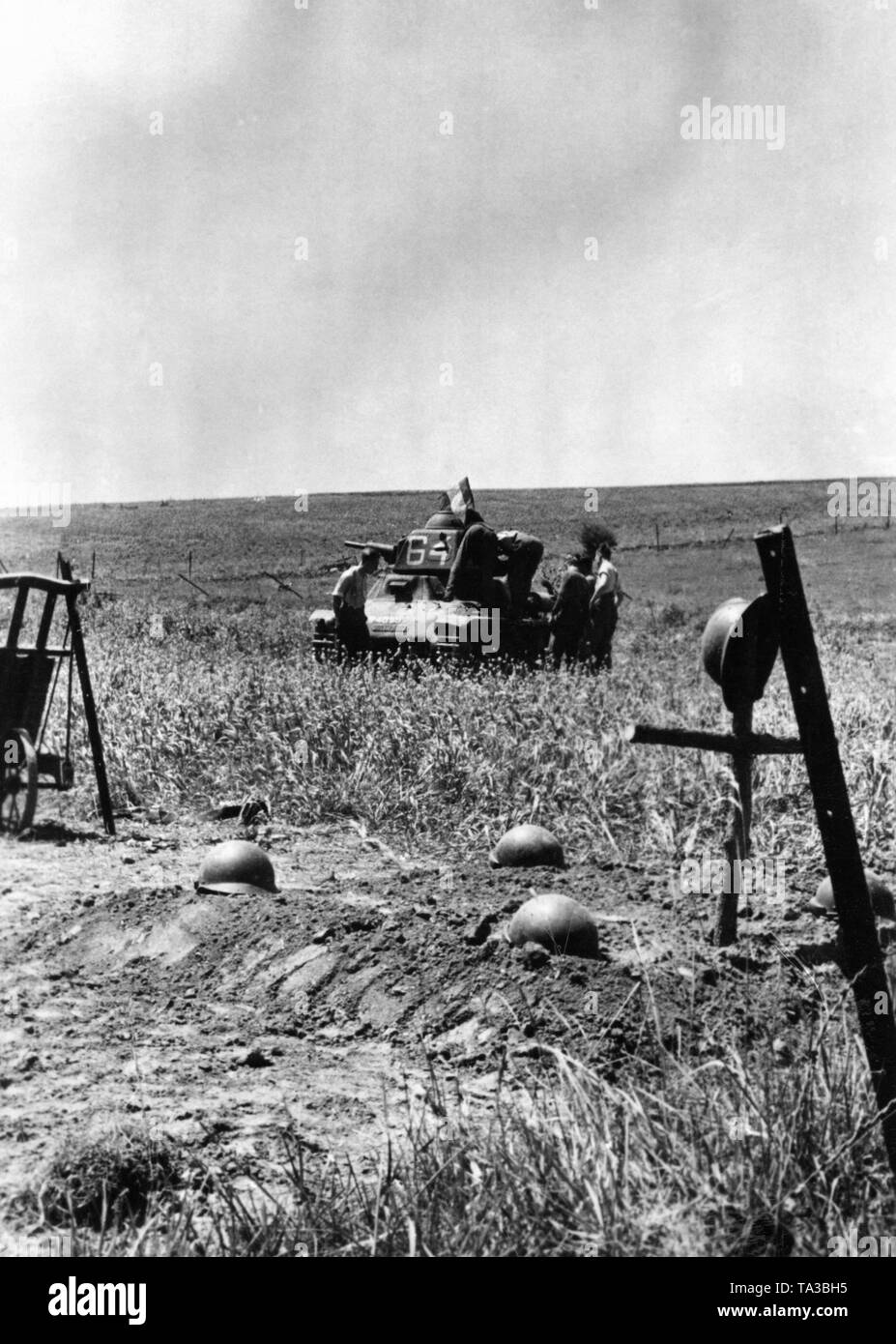 German soldiers examine a shot down French tank of the type Somua. In the foreground, graves of French fallen soldiers. Photo: Gutjahr Stock Photo