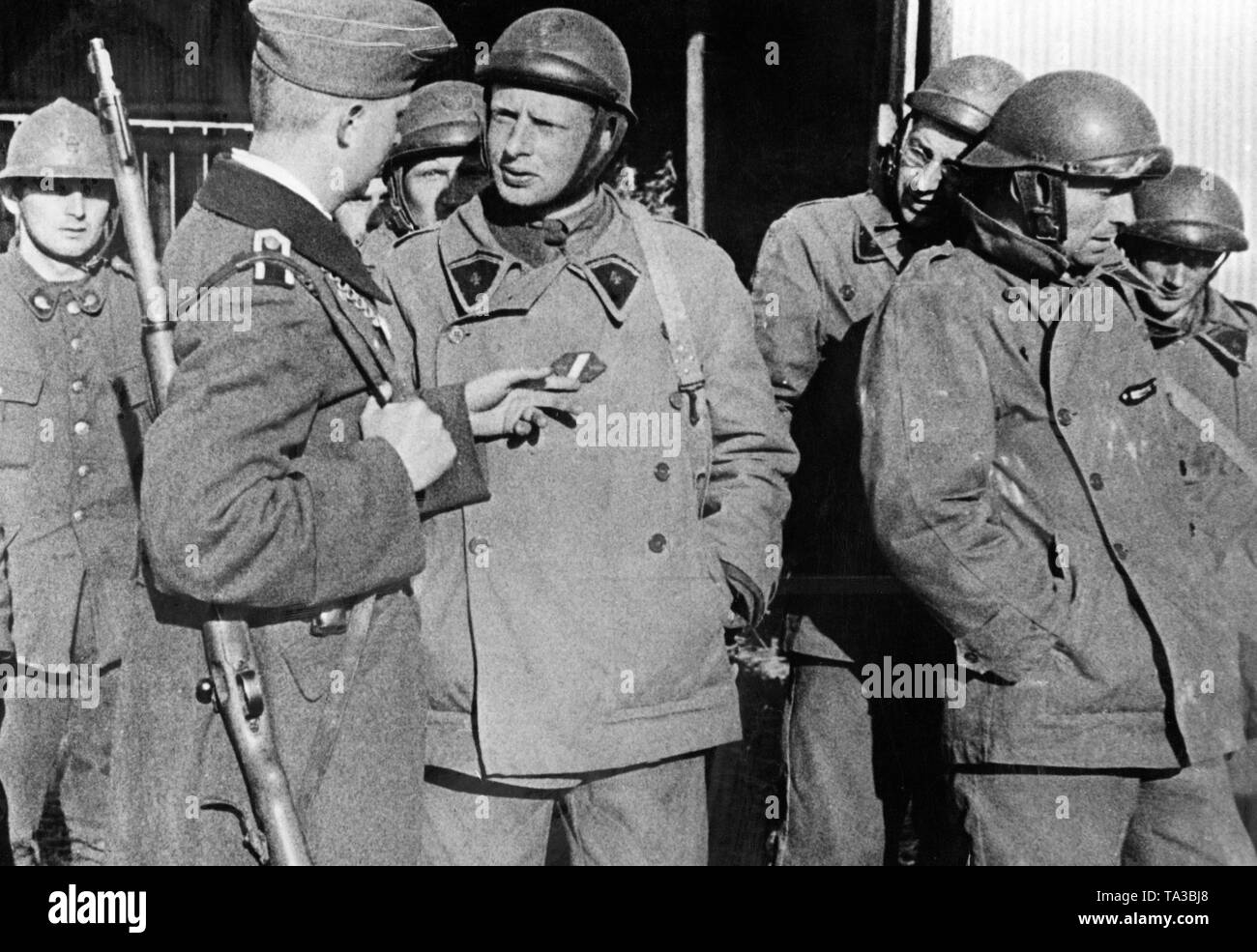 A member of the German Feldgendarmerie in conversation with French ...