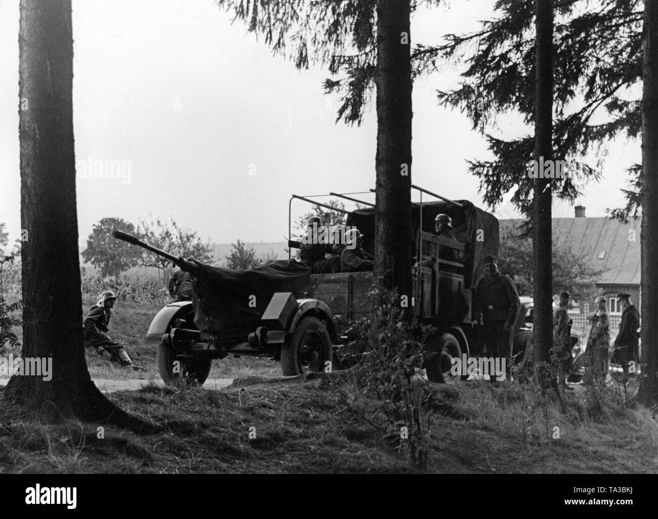During the autumn maneuvers in Mecklenburg soldiers make a stop at a forest edge with a light anti-aircraft gun. This is pulled by a truck of the Wehrmacht. The gun is a 2cm Flak 30. Stock Photo