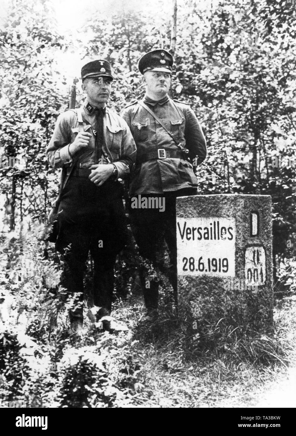 The inscription on the stone points to the demarcation of the Treaty of Versailles, which was unacceptable to the Germans, especially to the National Socialists. Here a man in an SS uniform (left) goes with a customs official on patrol. Stock Photo