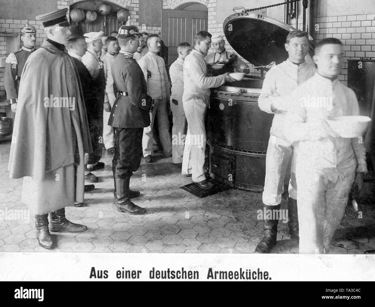 Soldiers of a guards regiment receive their food in their barracks in Berlin. A sergeant and an officer are supervising. Stock Photo