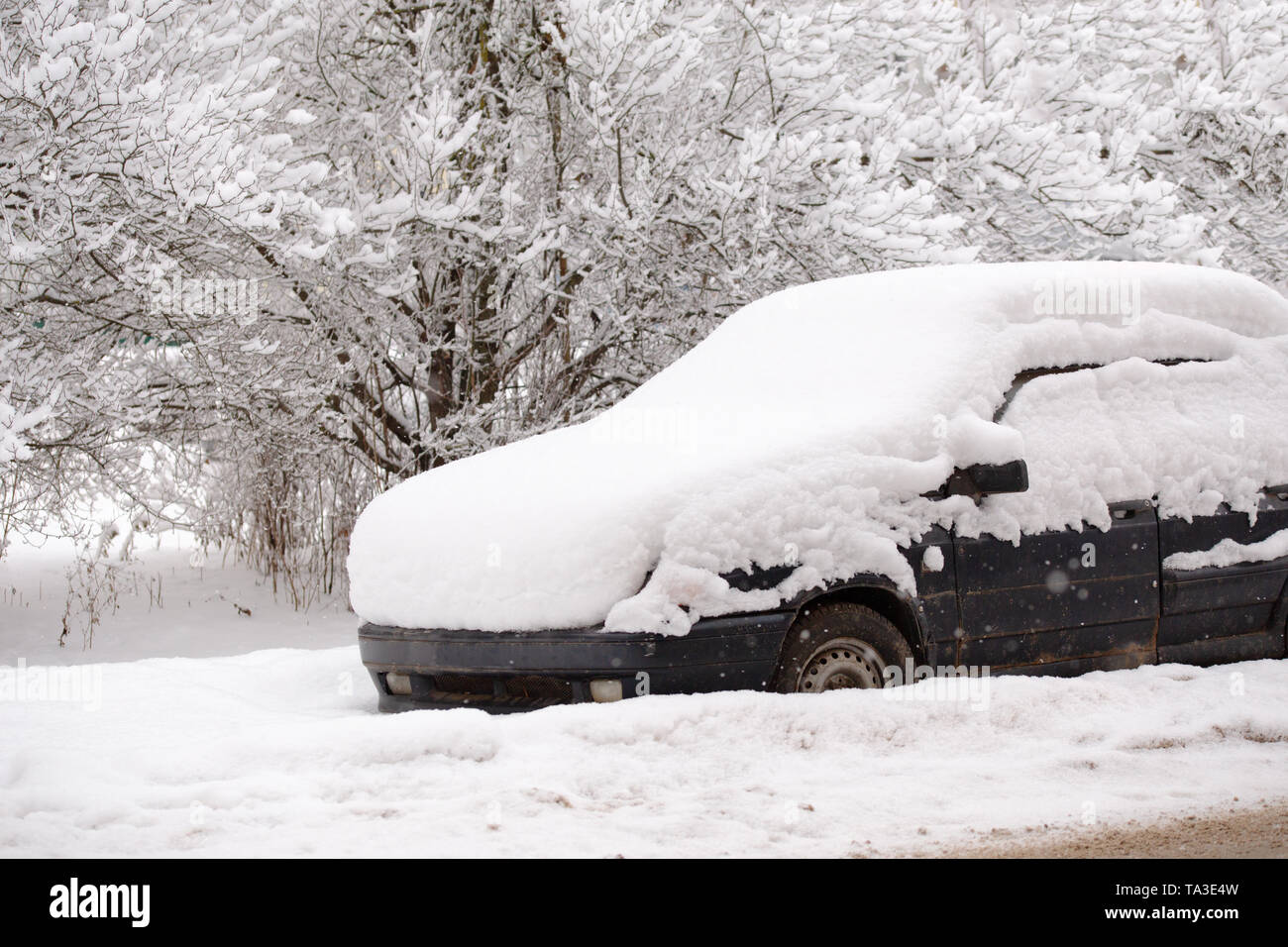 Old dirty car covered by thick snow layer with selective focus. Stock Photo