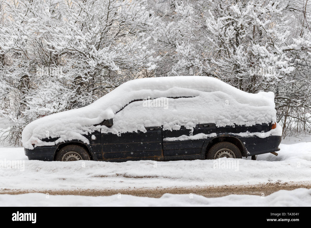 Old dirty car covered by thick snow layer with selective focus. Stock Photo