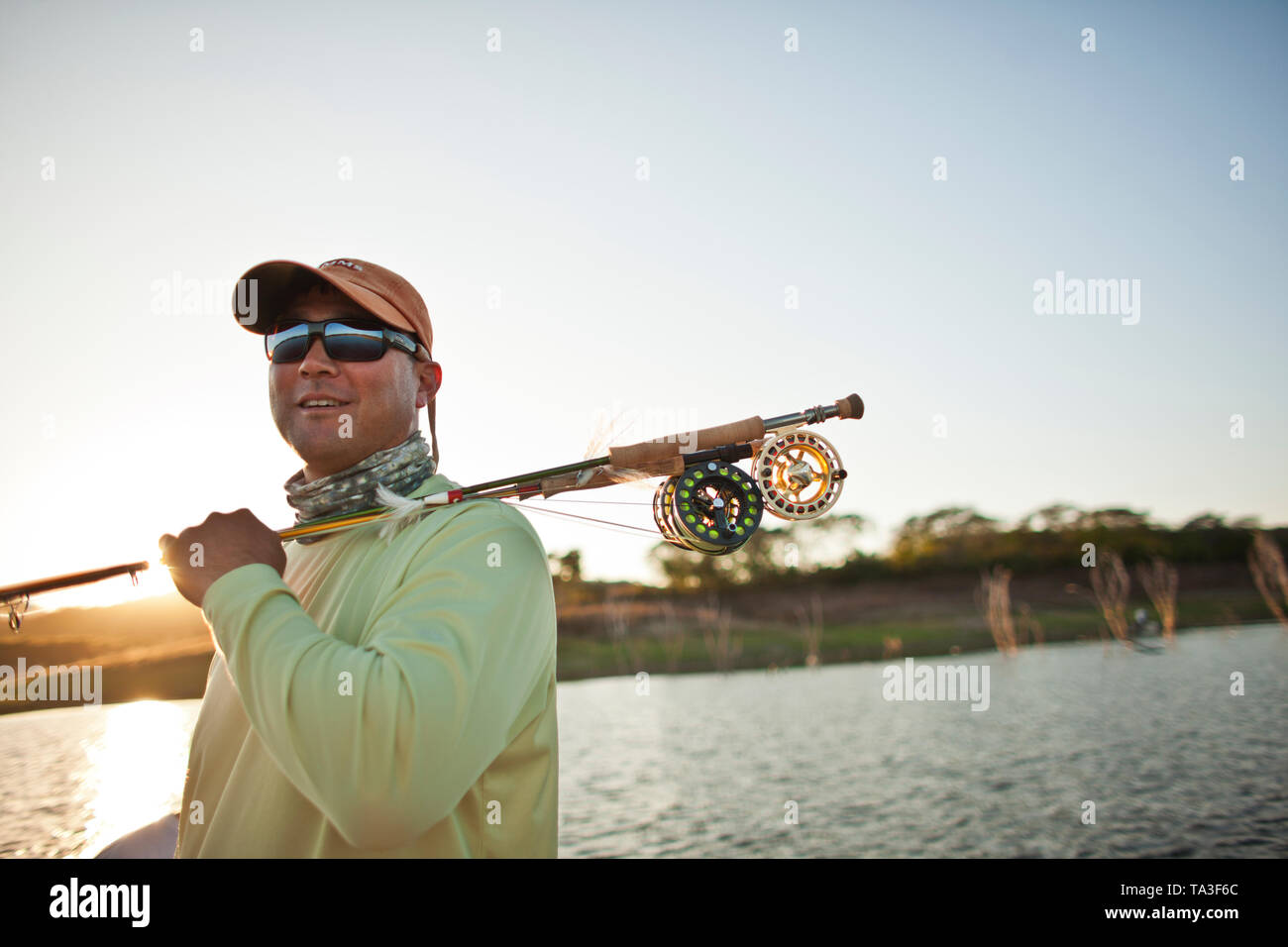 https://c8.alamy.com/comp/TA3F6C/smiling-mid-adult-man-carrying-a-fishing-rod-over-his-shoulder-while-at-a-lake-in-the-sunshine-TA3F6C.jpg