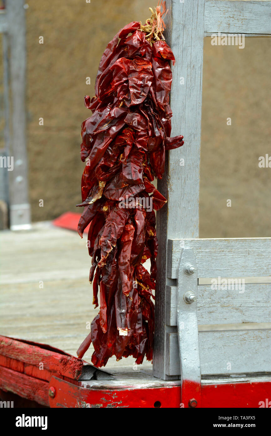 A string of dried chile pods, called ristras, hangs on a vintage railroad station baggage cart at the historic train depot in Lamy, New Mexico USA Stock Photo