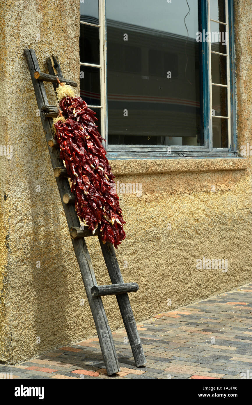 Strings of dried chile pods, called ristras, hang on a rustic ladder at the historic train depot in Lamy, New Mexico USA Stock Photo