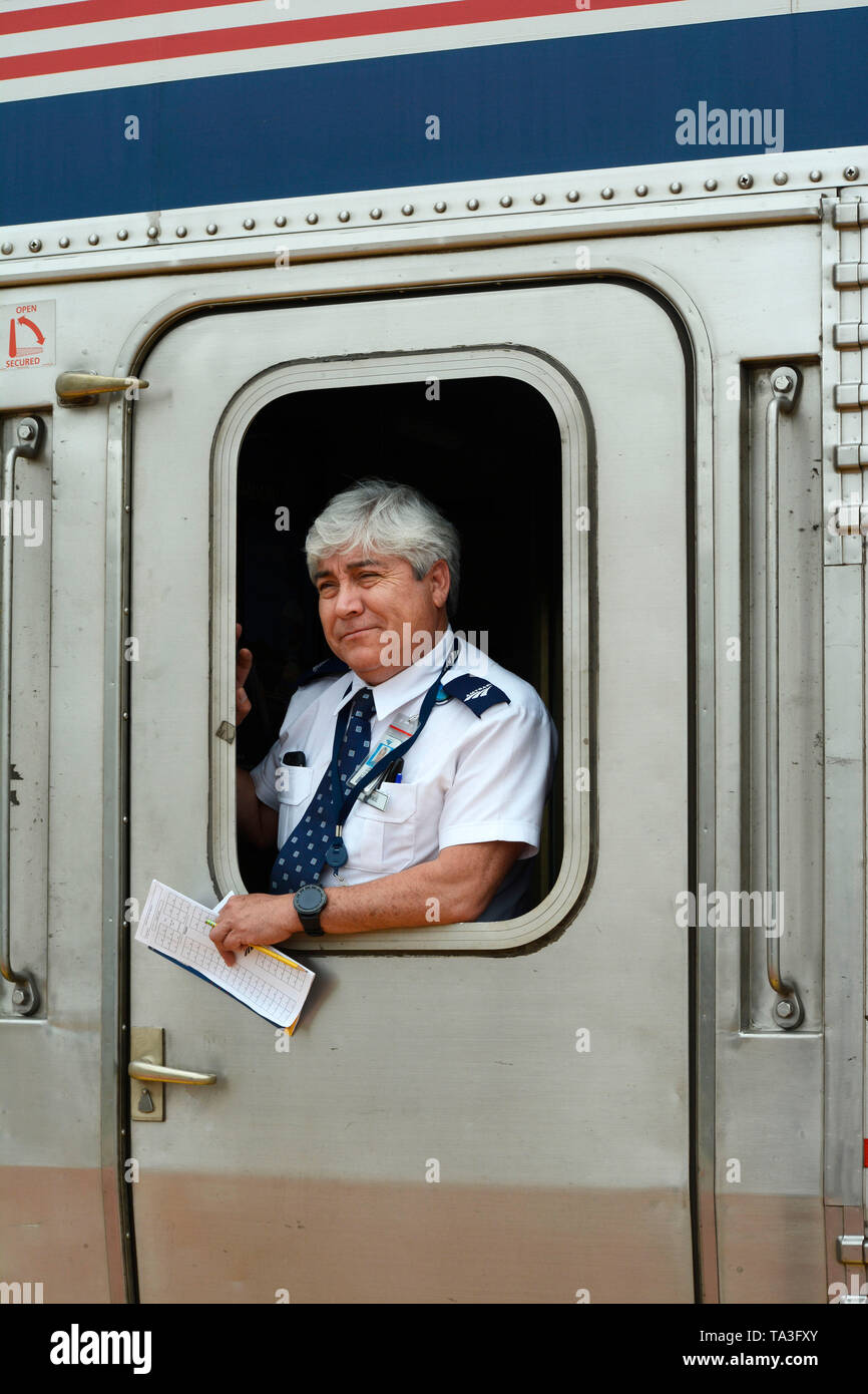 an-amtrak-assistant-conductor-stands-at-the-door-of-a-passenger-coach-of-an-amtrak-train-after-stopping-to-pick-up-passengers-at-the-train-depot-and-a-stock-photo-alamy