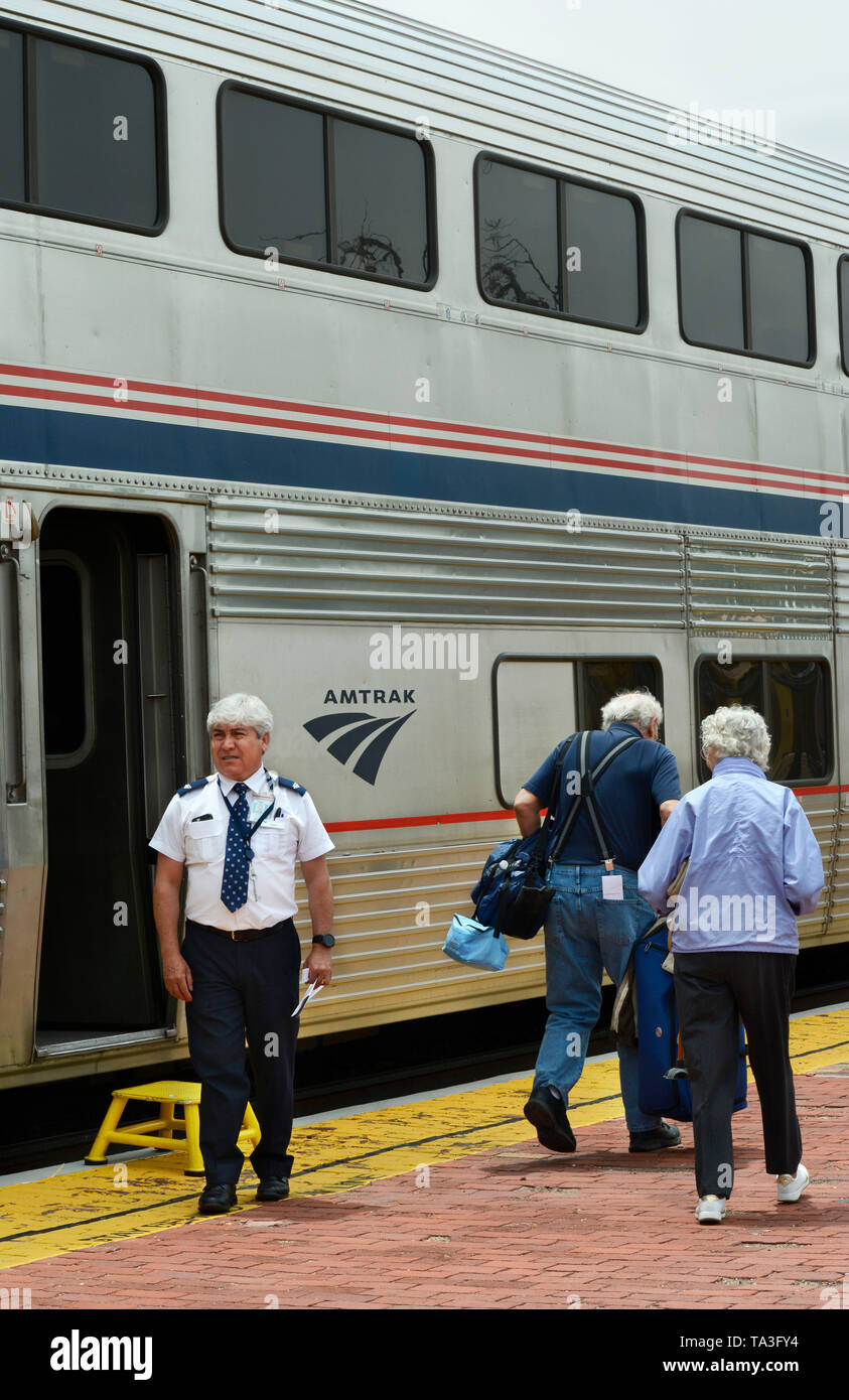 An Amtrak assistant conductor helps passengers board a train at the train depot and Amtrak stop in Lamy, New Mexico USA Stock Photo