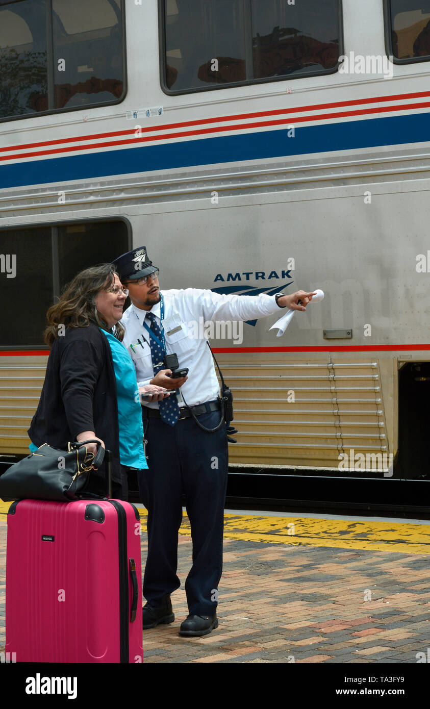 An Amtrak conductor helps passengers board a train at the railroad depot and Amtrak stop in Lamy, New Mexico USA Stock Photo