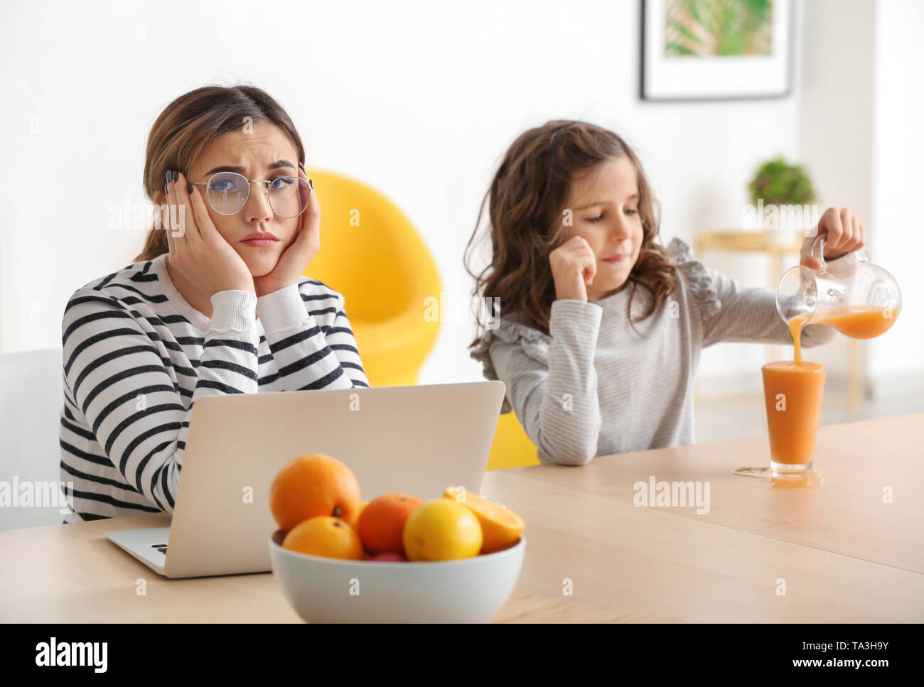 Tired mother with naughty daughter working at home Stock Photo