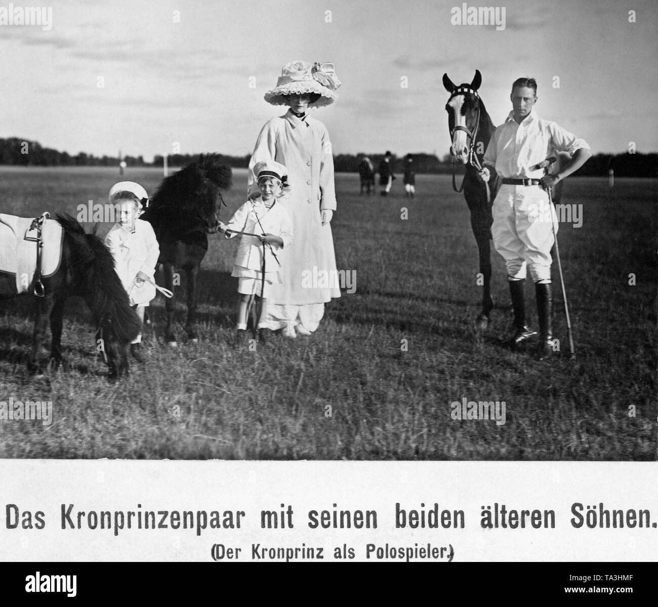 From left to right: Prince Louis Ferdinand, Prince William, Crown Princess Cecilie, Crown Prince Wilhelm.  The picture was made probably during a polo game of the Crown Prince. The two children steady their riding ponies while Crown Prince Wilhelm is dressed as a polo player and stands with a racket in his hand next to his horse. Stock Photo