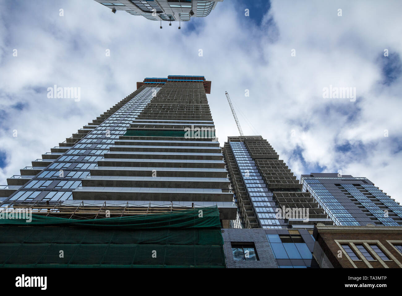 Cranes and building device on a construction site of a skyscraper in downtown Toronto, surrounded by other high rise towers and condos as well as olde Stock Photo