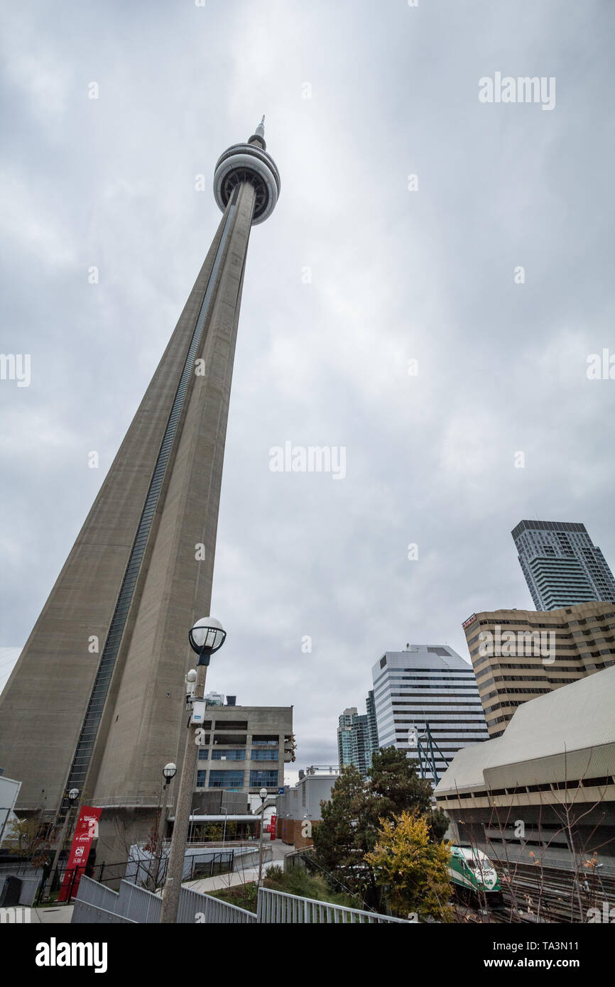 TORONTO, CANADA - NOVEMBER 13, 2018: View of the Canadian National Tower (CN Tower)  from its bottom with trains passing by. It is one of the main lan Stock Photo