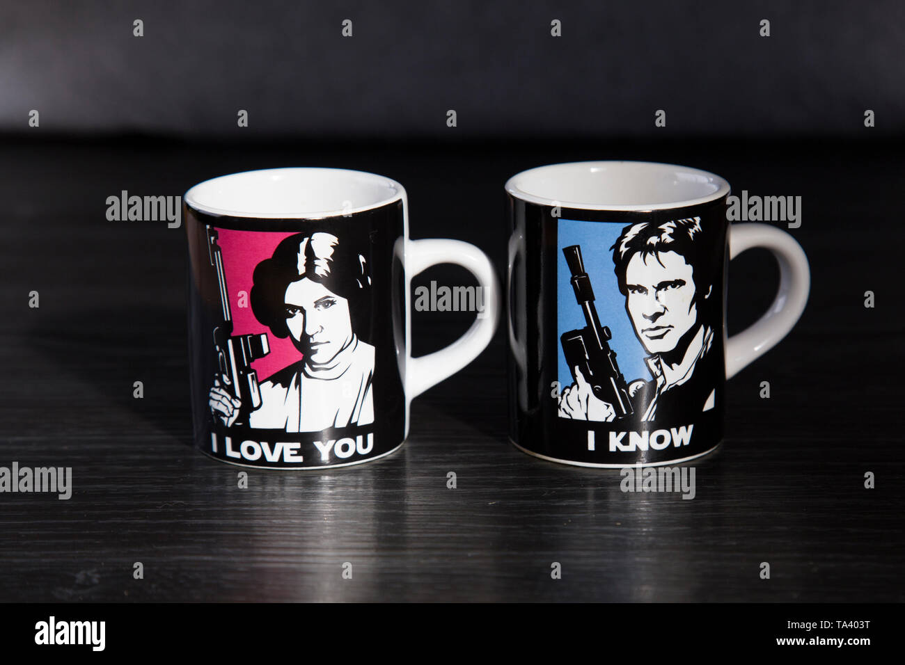 Two Star Wars branded espresso cups. One with Princess Leia saying I love you and the other with Han Solo saying I know. On wooden bench top. Stock Photo