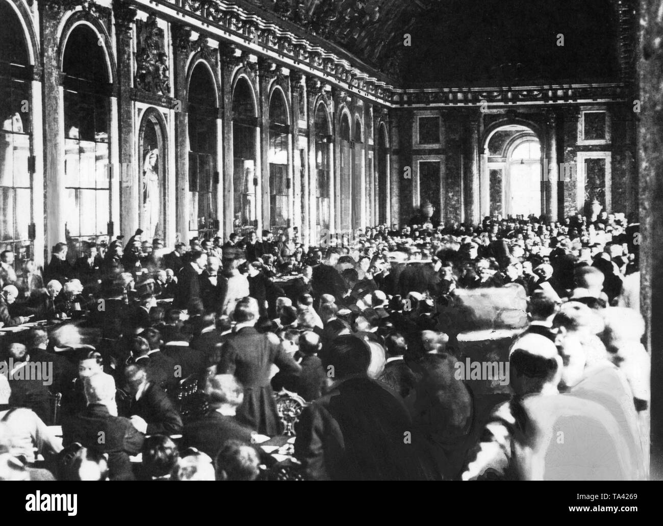 The German Foreign Minister Hermann Mueller and the Minister of Transport Johannes Bell sign the Treaty of Versailles. Hundreds of people are present in the Mirror Hall of Versailles. The German National Assembly has authorized the government to sign only after weeks of struggle. Stock Photo