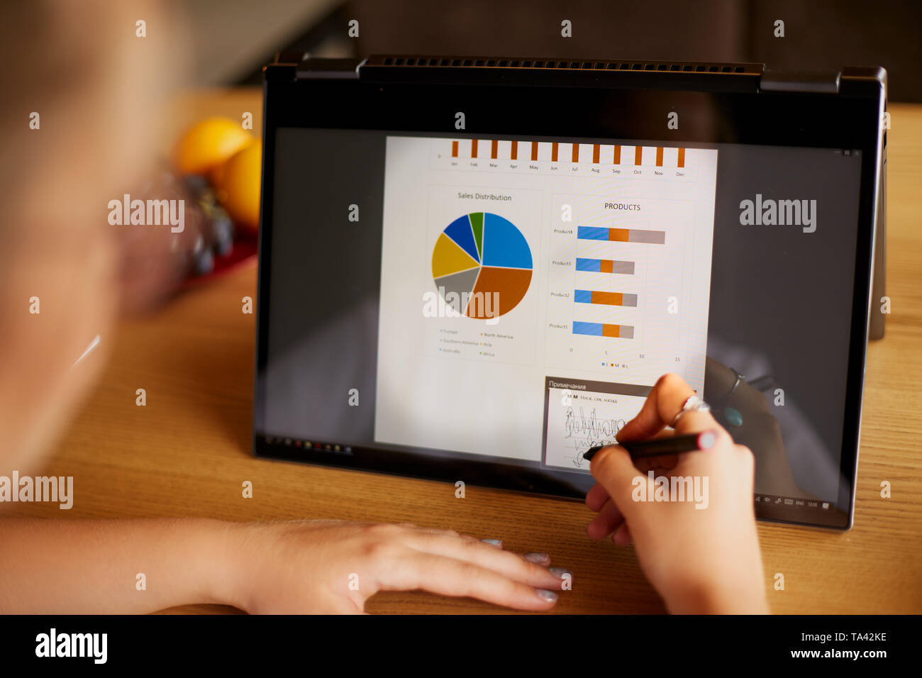 Businesswoman hand pointing with stylus on the chart over hybrid convertible laptop screen. Woman using 2 in 1 notebook for work on business presentat Stock Photo