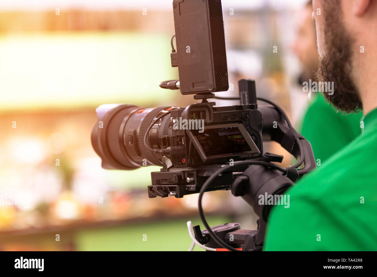 Videographer shooting a film or a television program in a studio with a professional camera, backstage Stock Photo