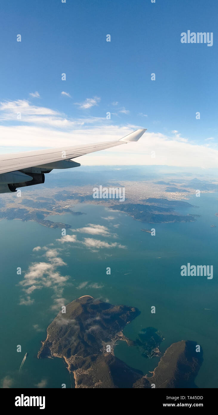 View from airplane window on the wing over Tokyo in Japan. Flying and traveling above the clouds Stock Photo