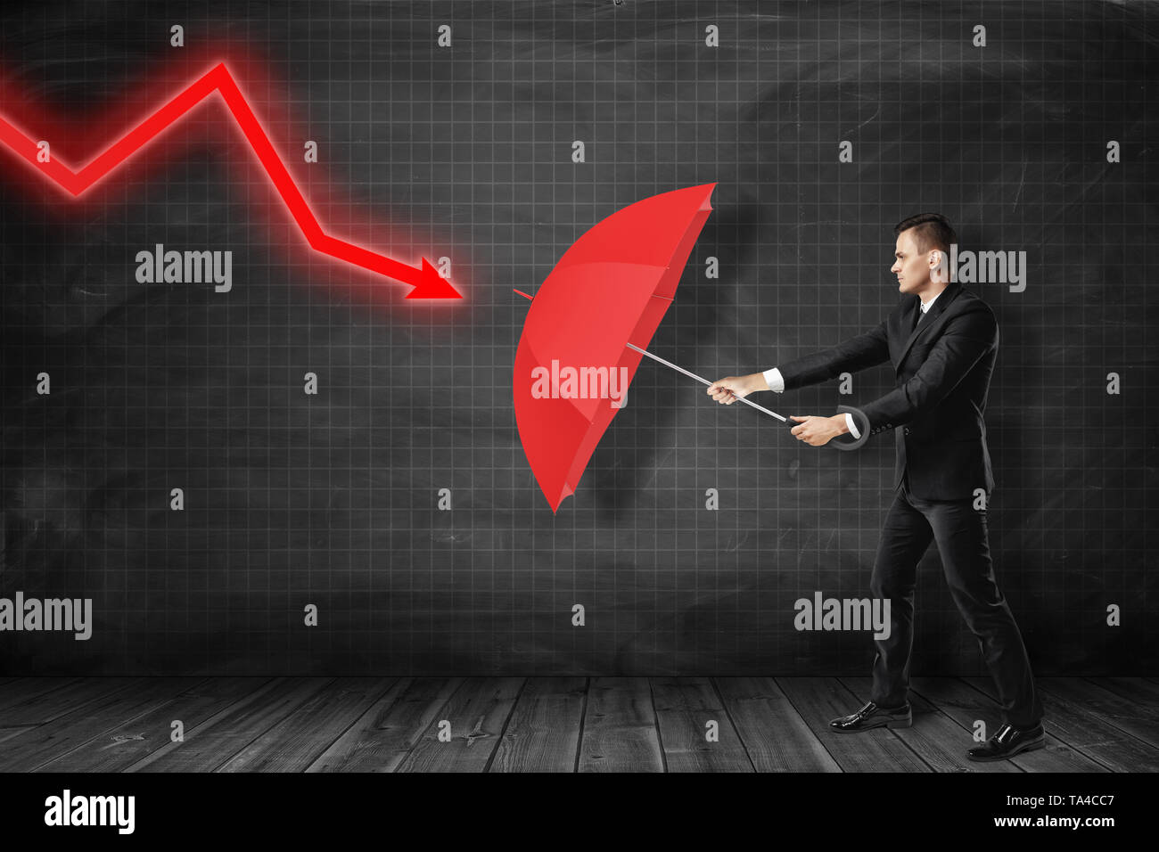 Businessman protecting himself with red umbrella against red diagram ...