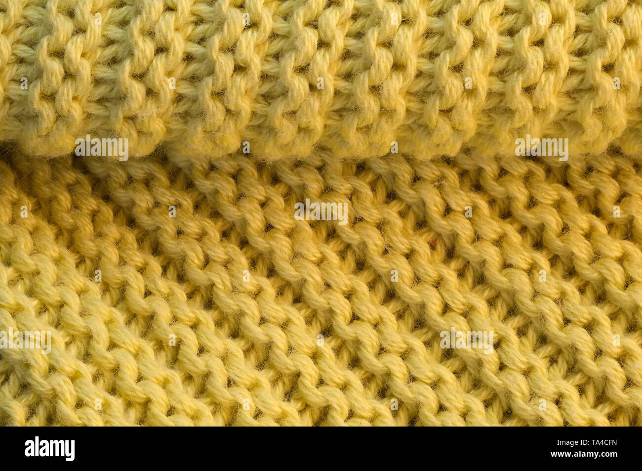 Artistic background from yellow knitted wool fabric with large loops macro photography Stock Photo