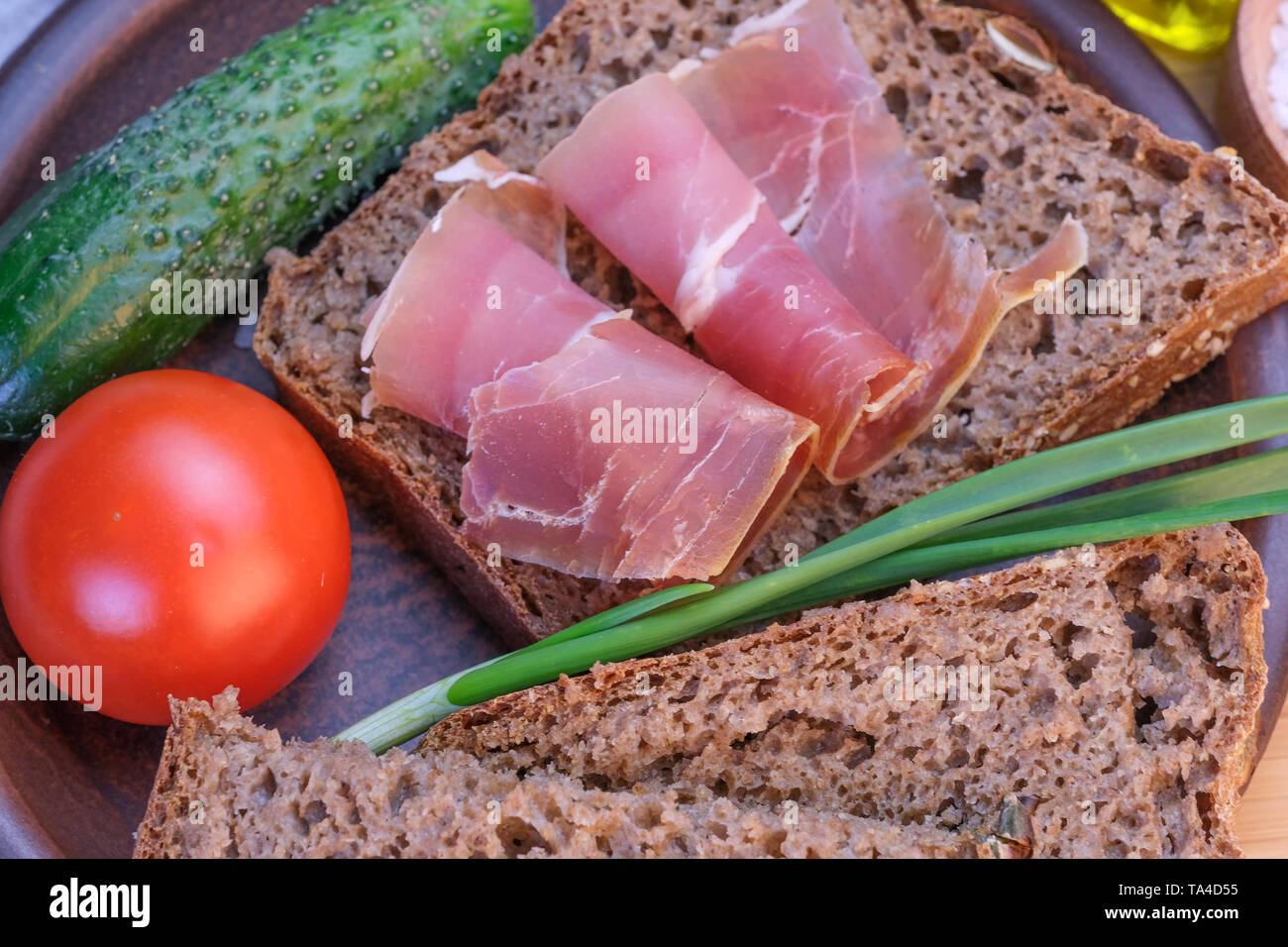 Snack with homemade rye bread and dried pork on a brown clay plate close-up Stock Photo