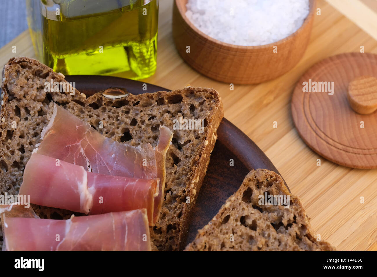 Snack with homemade rye bread and dried pork on a brown clay plate close-up Stock Photo