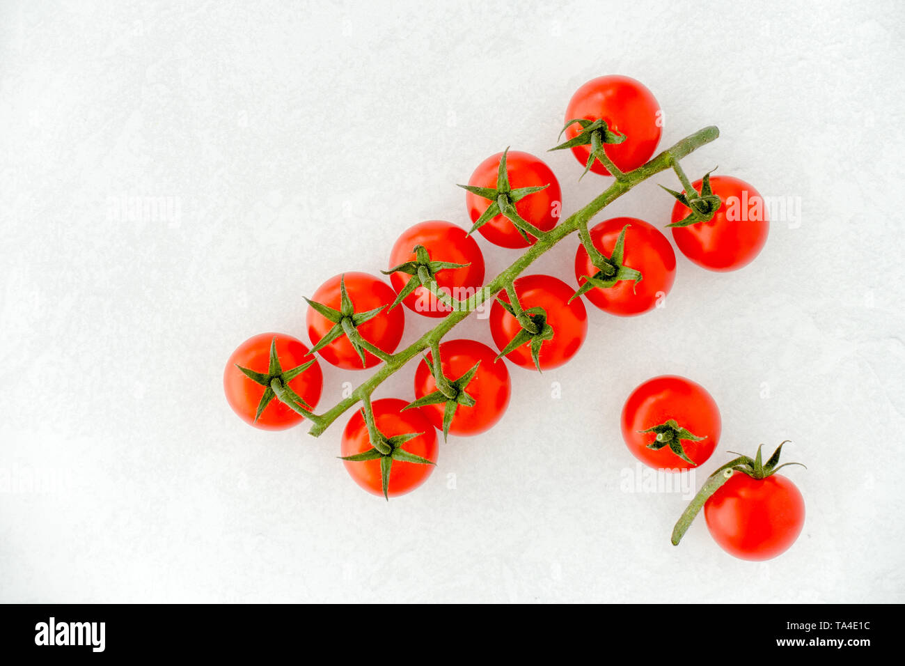 Arrangement of cherry tomatoes on white textured and patterned background with copy space. Top view. Stock Photo