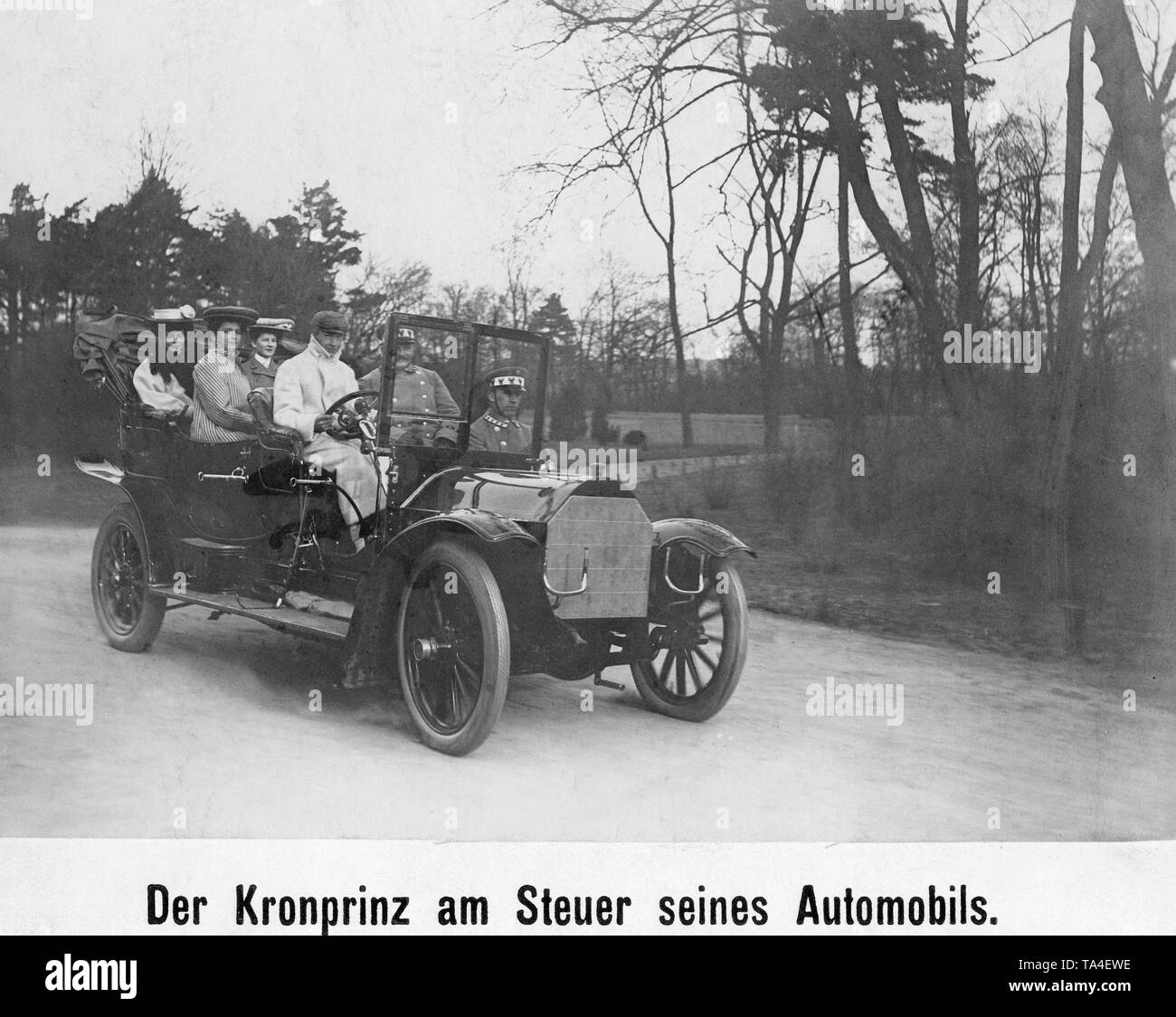Crown Prince Wilhelm (front left) at the wheel of his automobile. In the back of the car, sits his wife, Crown Princess Cecilie of Prussia, born Duchess of Mecklenburg (behind left with a white hat), with two of her court ladies. Stock Photo