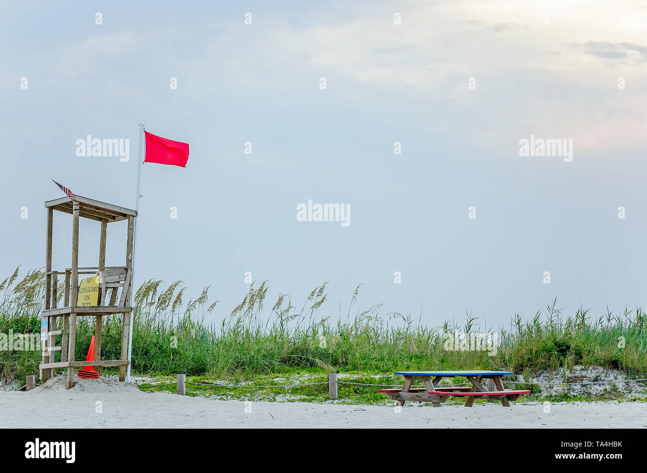 A red flag flies from an empty lifeguard stand, Aug. 2, 2014, in Dauphin Island, Alabama. The red flag signifies hazardous conditions like rough surf. Stock Photo