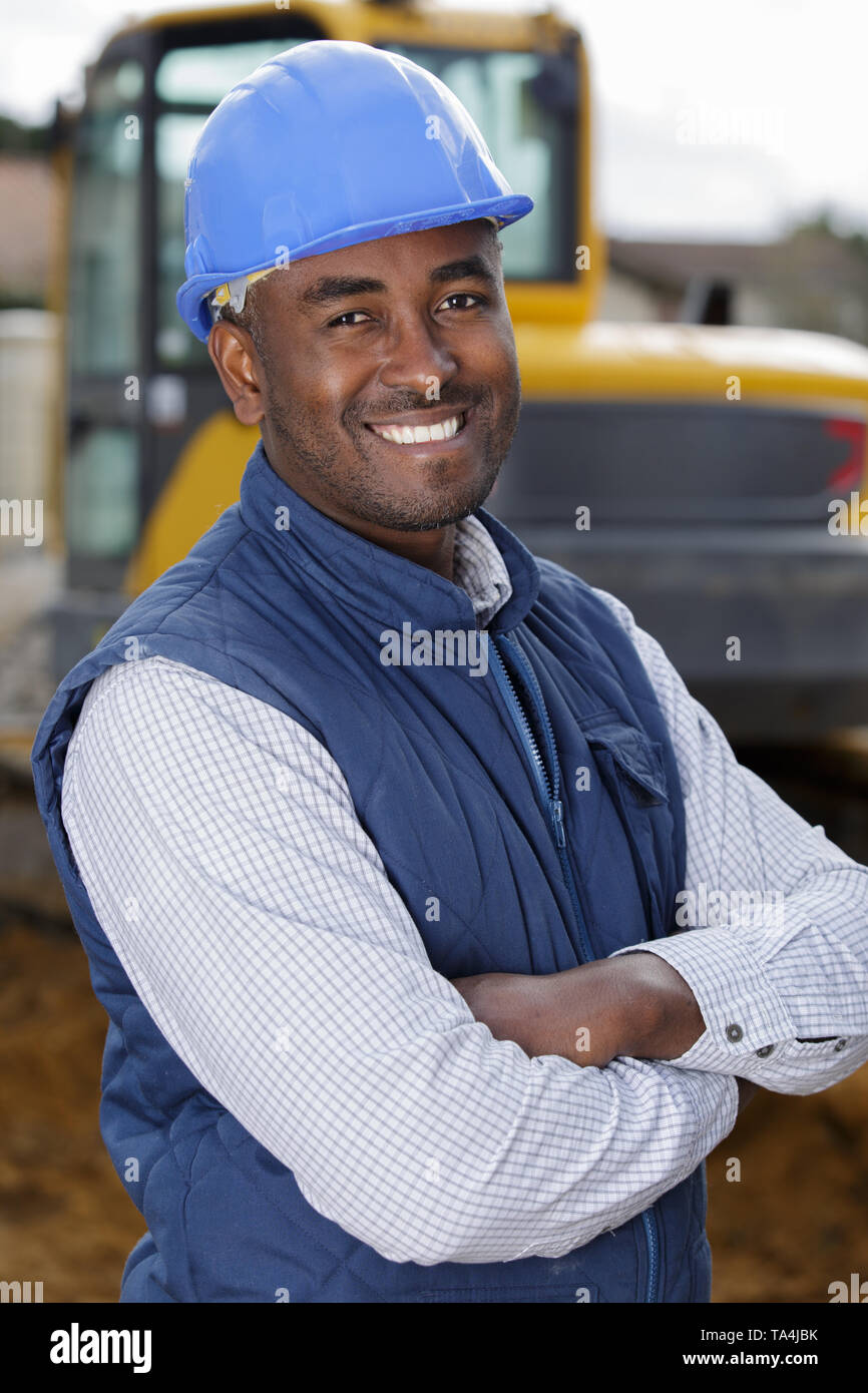 man driver posing near excavator backhoe in construction site Stock