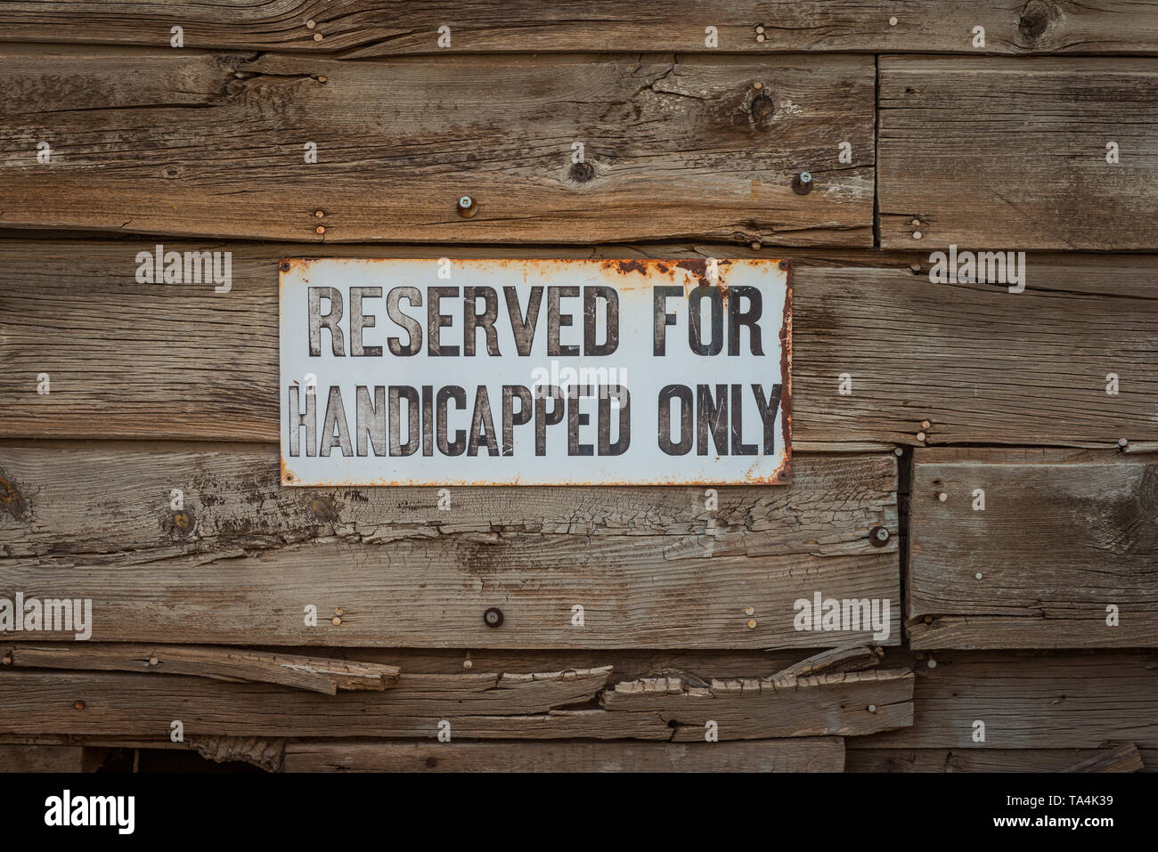 An old white sign for reserved handicap parking. Stock Photo