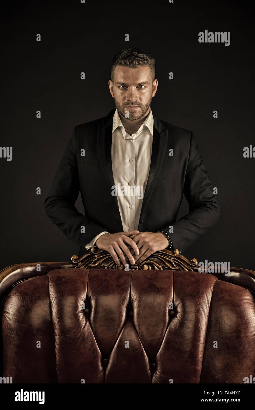 Confidence and charisma. Man stand at leather armchair on dark background.  Bearded man in formal suit. Businessman with beard and hairstyle. Business  fashion style and trend, vintage filter Stock Photo - Alamy