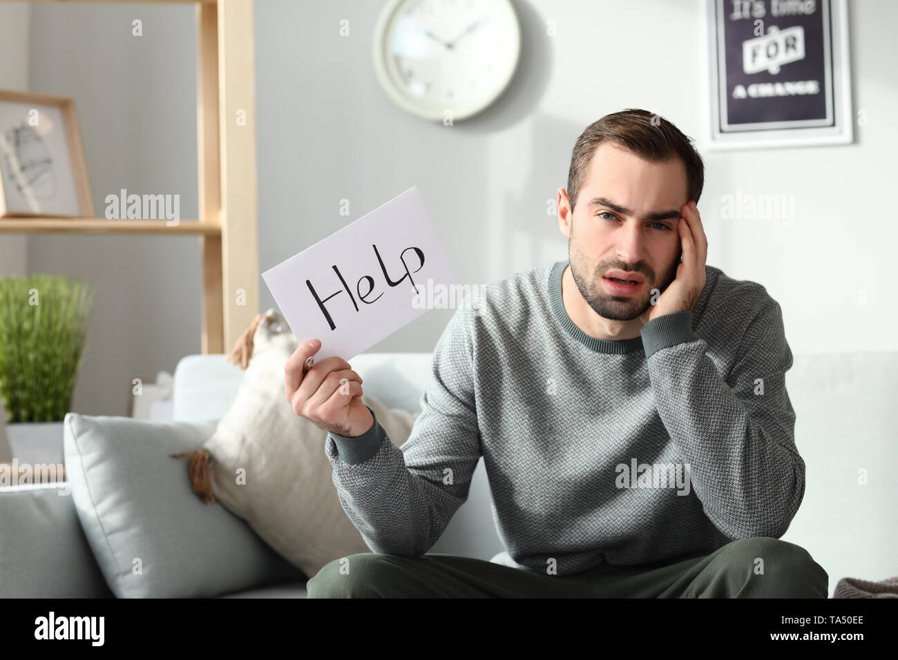 Young man in debt holding paper sheet with text HELP at home Stock ...