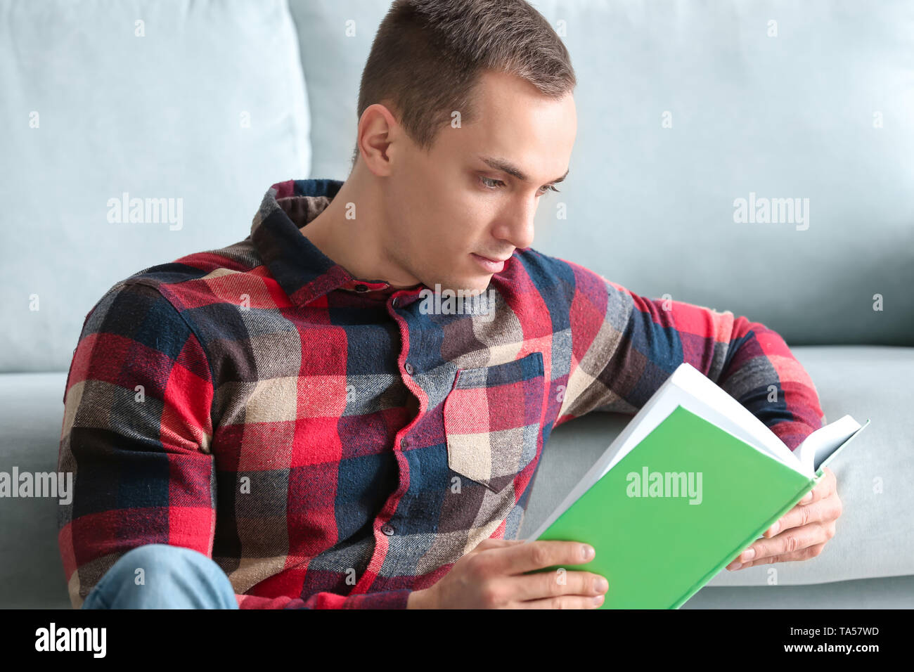 Handsome young man reading book at home Stock Photo - Alamy