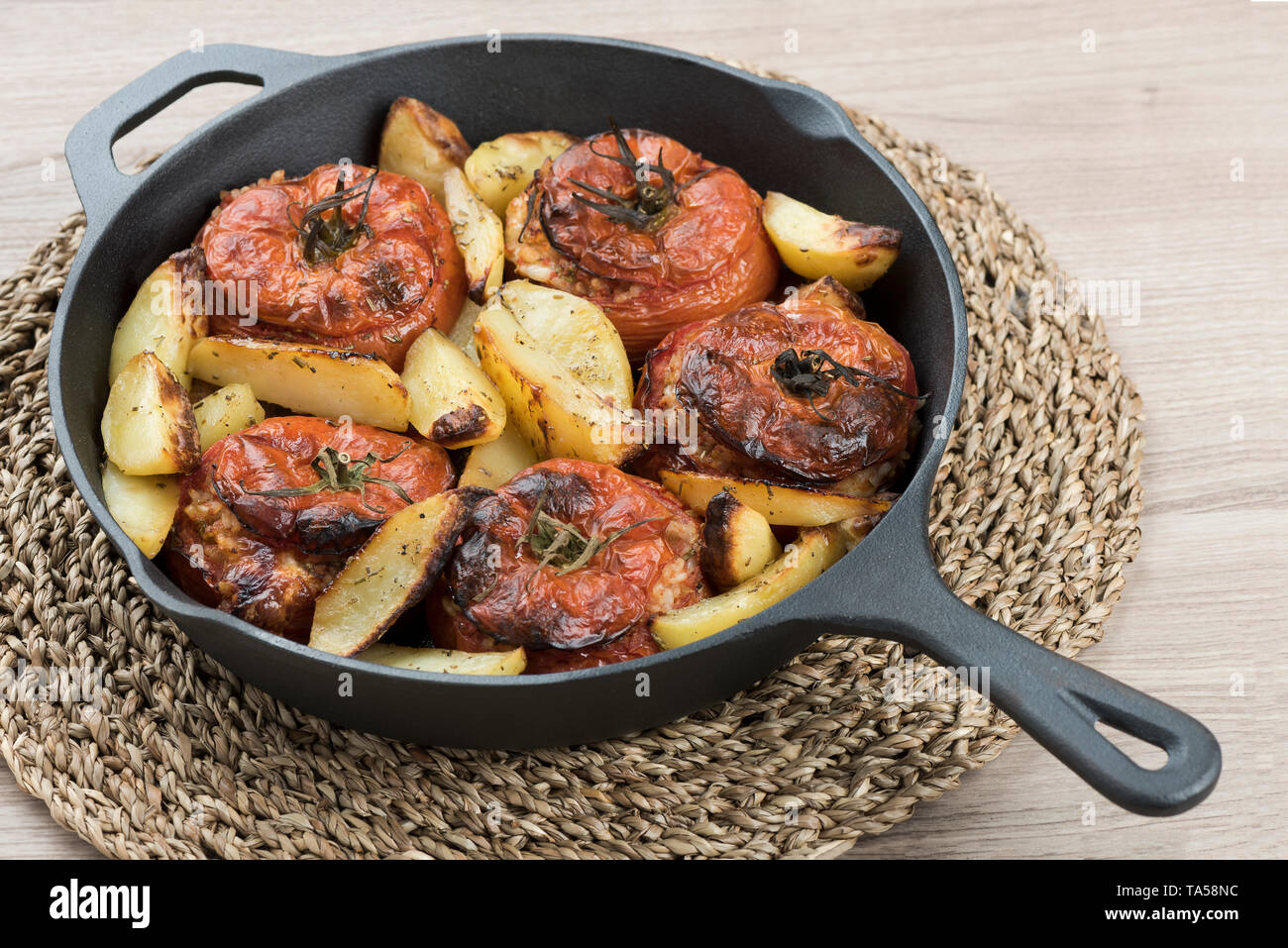 https://c8.alamy.com/comp/TA58NC/cast-iron-pan-with-tomatoes-with-rice-and-baked-potatoes-on-centerpiece-and-light-background-TA58NC.jpg