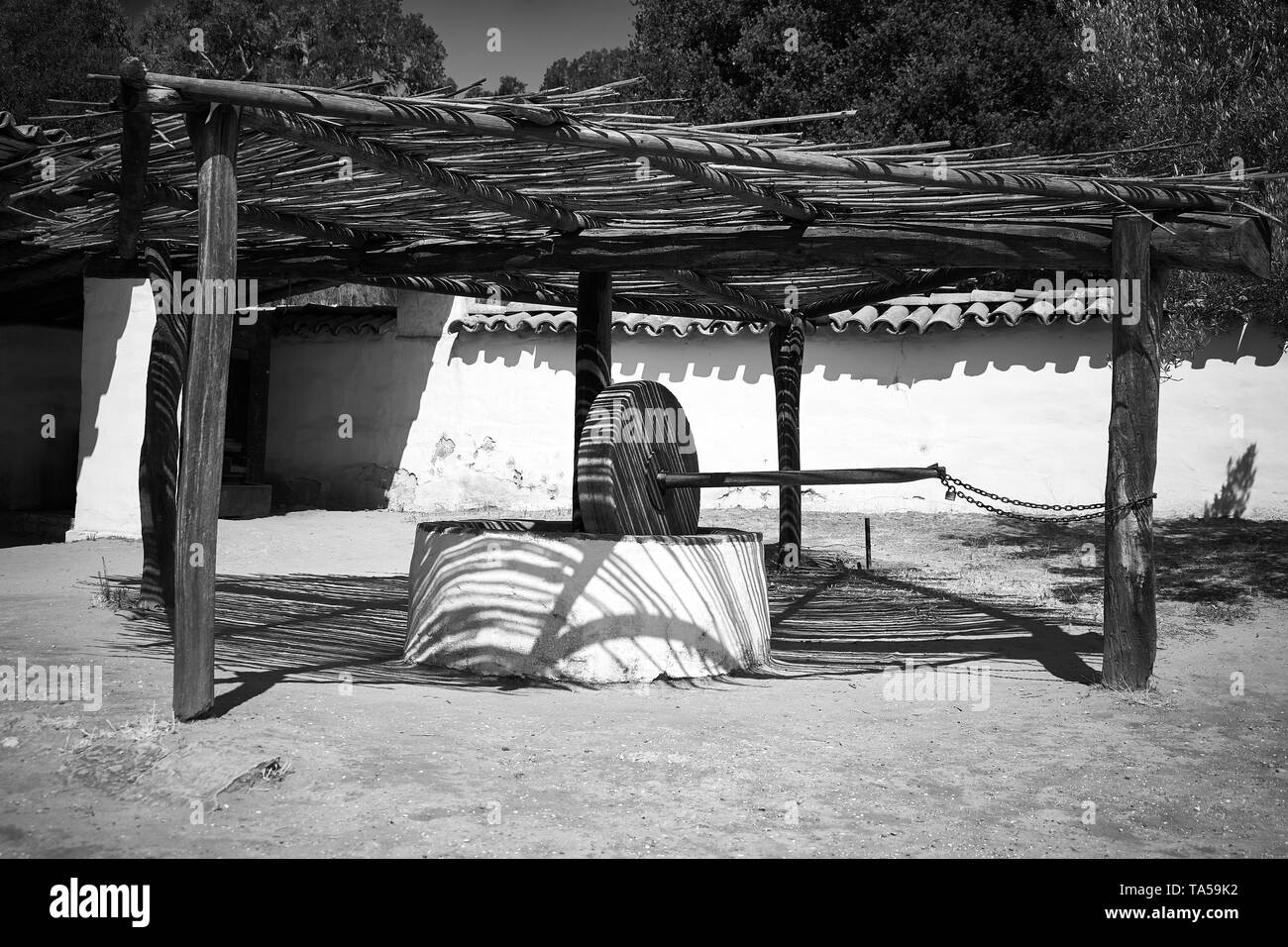 A stone grain mill under a bamboo roof on a sunny day at La Purisima Mission in Lompoc, California. Stock Photo