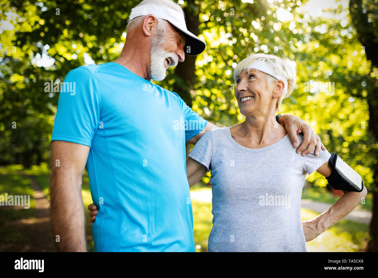 Healthy mature couple jogging in a park at early morning with sunrise Stock Photo