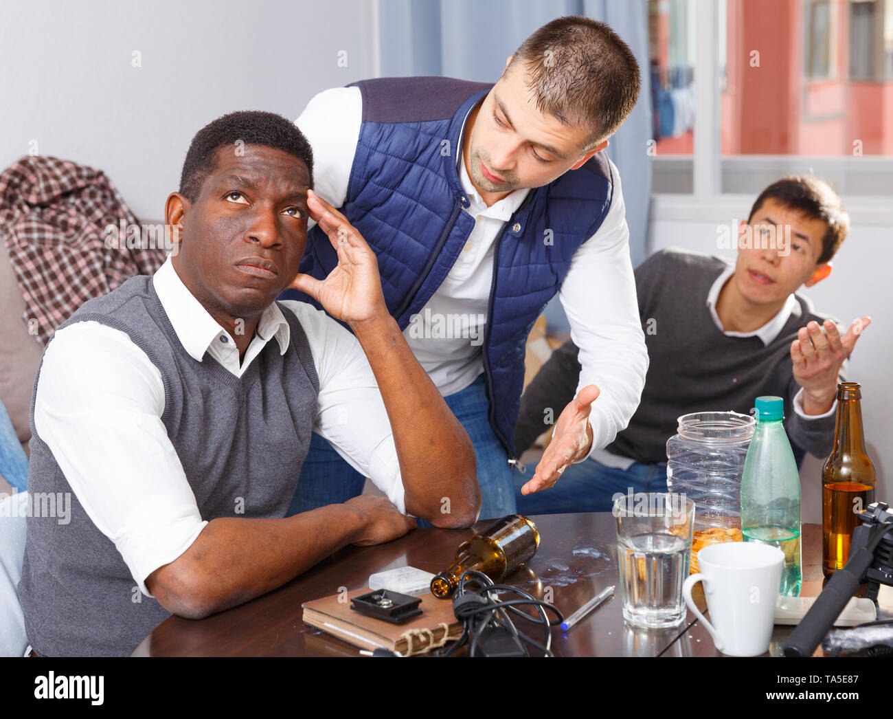 Chagrined young man sitting at home table having problems in ...