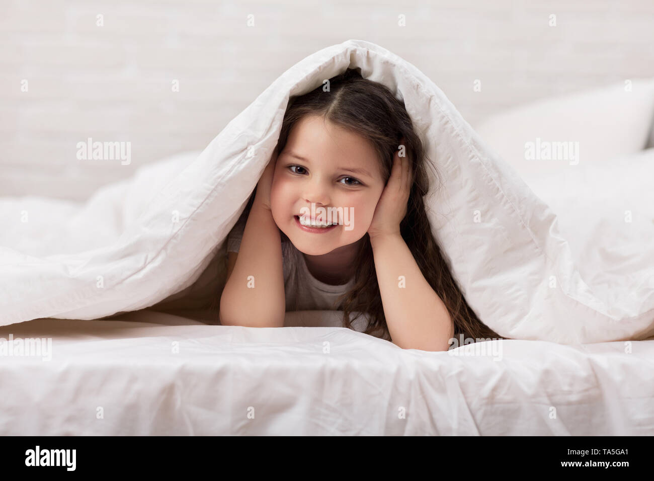 happy morning baby in bed. child dabbles in bed. child covers his ears