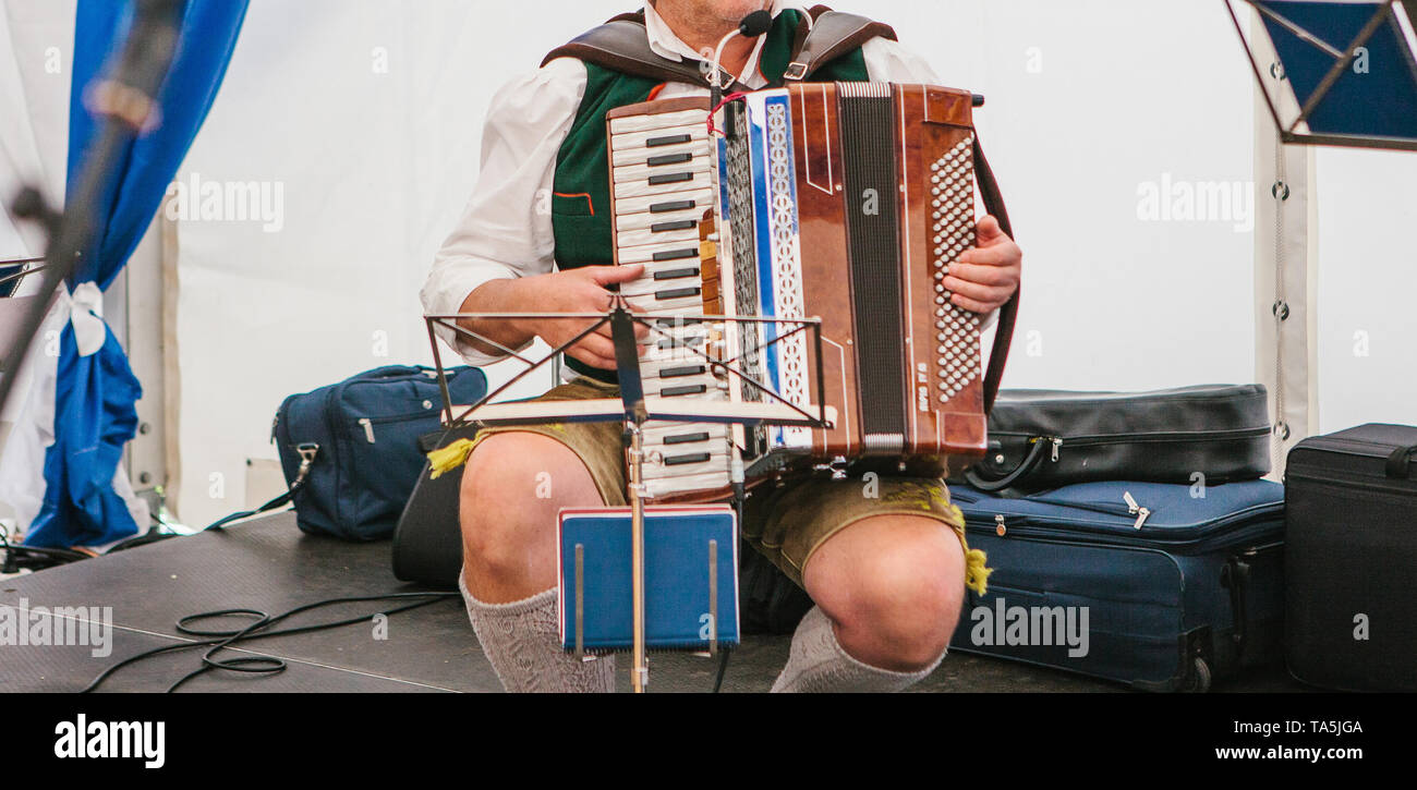 An accordionist in traditional Bavarian clothes plays the accordion on